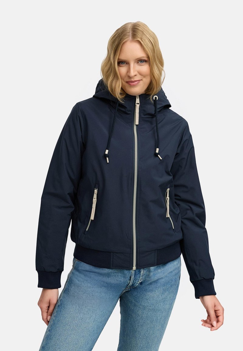 Tums zilas kapucēta jaka ar priekšējo rāvējslēdzēju, divām sānu kabatām un kontrastējošām krēmkrāsas detaļām. Ribota aproce un apakša. Gluda, viegla auduma.