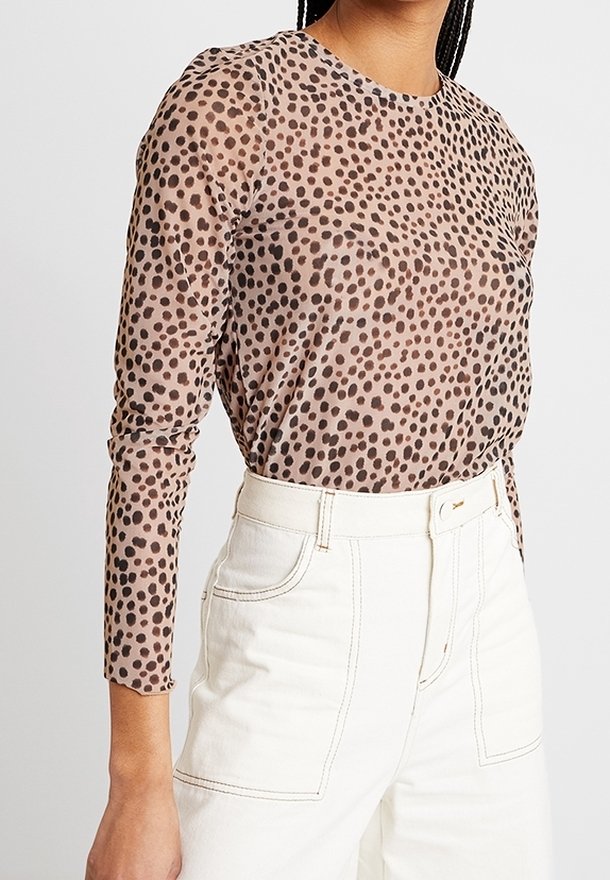 Pitkähihaisen puseron semi-transparentti kangas, jossa on vaaleanruskea pohjaväri ja tummanruskeita leopardilaikkuja, pyöreä kaula-aukko ja istuvat hihansuut.