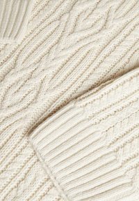 Cream-colored knitted sweater featuring a textured cable pattern and ribbed accents, showcasing a soft, woven fabric and raised stitches.