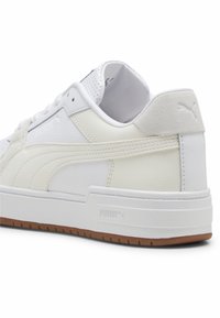 Vita sneakers med en överdel i slätt läder och mocka, vadderad krage och gummisula med texturerat brunt mönster. PUMA-logotyp på sidan.