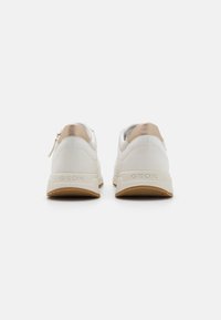Sneaker bianche con una superficie testurizzata, dettagli beige e punta arrotondata. Caratterizzate da un logo del marchio visibile sul tallone e una suola in gomma.