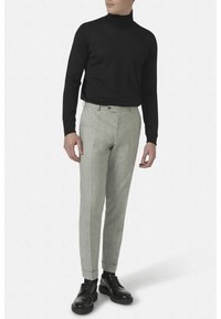 Czarny sweter z kołnierzem typu stójka w połączeniu z jasnoszarymi, dopasowanymi spodniami. Spodnie mają teksturowany materiał i slim fit, uzupełnione czarnymi butami.