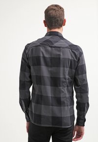 Schwarz-grau kariertes Langarmhemd aus Baumwollmaterial, mit geknöpften Manschetten, Rückenteil mit Passe, schlanker Schnitt, glatter Textur.