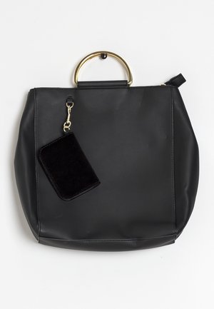 Sac à main en cuir noir avec une anse ronde en métal doré et une petite pochette noire attachée suspendue à une fermeture dorée.