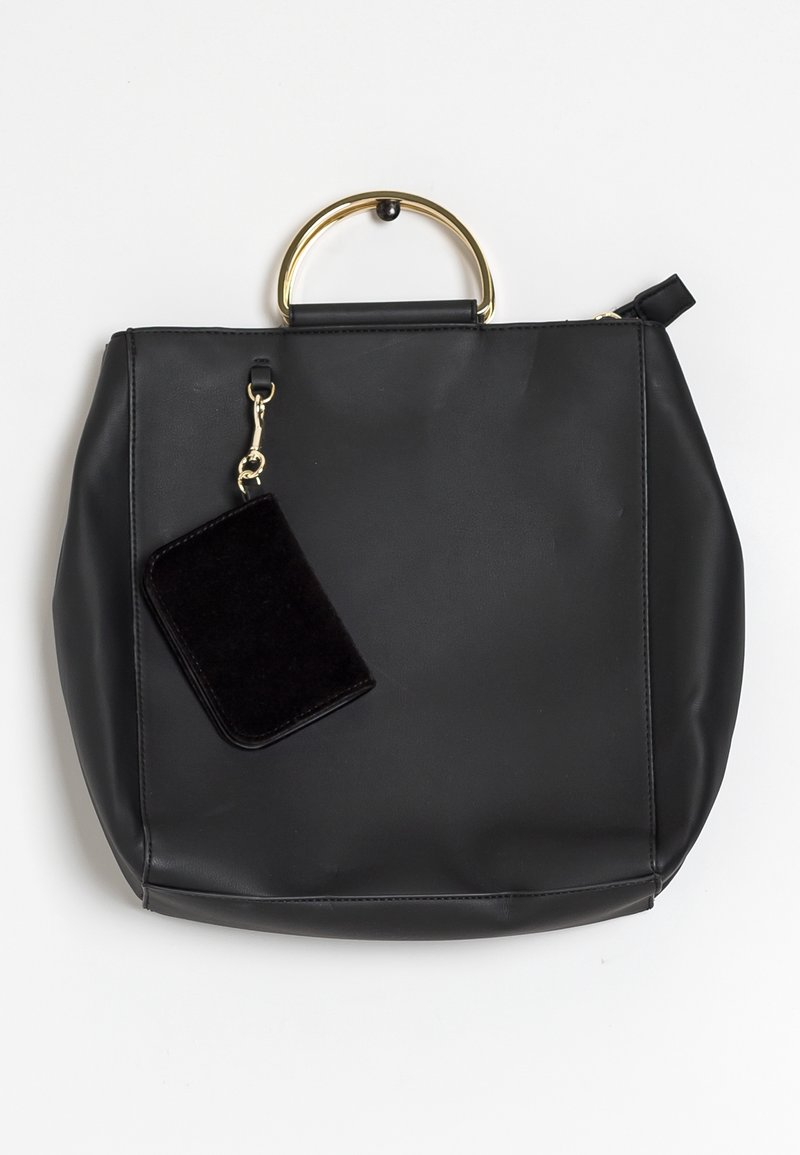 Sac à main en cuir noir avec une anse ronde en métal doré et une petite pochette noire attachée suspendue à une fermeture dorée.