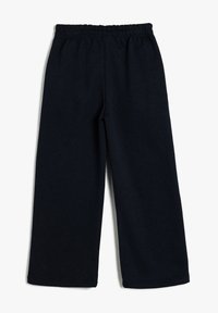 Pantalones de tela elástica negra con diseño de pierna ancha, cinturilla elástica y textura suave, que exhiben un estilo simple y versátil.