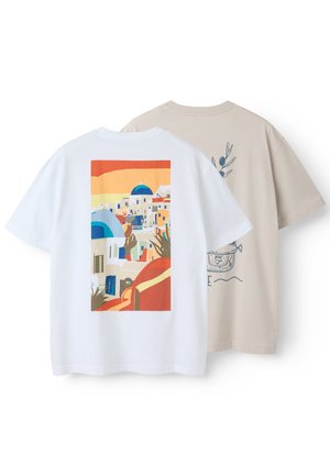 Zwei kurzärmelige T-Shirts, eines weiß mit einem bunten Druck eines mediterranen Dorfes, eines beige mit einer blauen botanischen und Topf-Illustration auf der Rückseite.