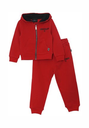 Tuta in cotone rosso con zip, dotata di cappuccio foderato di nero e tasche frontali, abbinata a pantaloni coordinati con dettagli stampati.