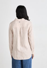 Striped long-sleeve shirt in light beige and rust colors. Soft fabric with a collared neckline and rounded hem. Back features a sewn label.