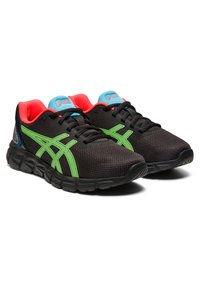 Zapatillas deportivas negras con acentos verdes vibrantes, parte superior de malla transpirable, cuello acolchado y forro interior rojo contrastante.