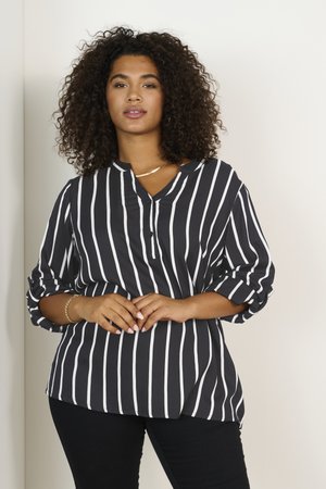 Blouse rayée noir et blanc avec un col en V, des manches trois quarts et une fermeture à bouton à l'avant. Tissu léger avec une coupe ample.