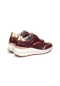 Baskets en cuir bordeaux avec des accents dorés, des détails texturés et une semelle blanche épaisse. Présente un design à lacets et des clous décoratifs.