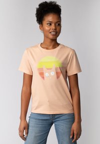 Perzikkleurig katoenen t-shirt met een ronde afbeelding van een kat en zonsondergangstrepen in geel, oranje en rood. Korte mouwen en ronde hals.