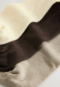 Drie overlappende textielaanslagen in crèmekleur, bruin en lichtbeige. De stof heeft een zachte textuur met een gladde gebreide afwerking.