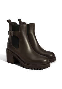 Bruine leren enkelboots met een chunky hak, elastische zijkanten en een zijgesp accent. Getextureerde rubberen zool voor grip.