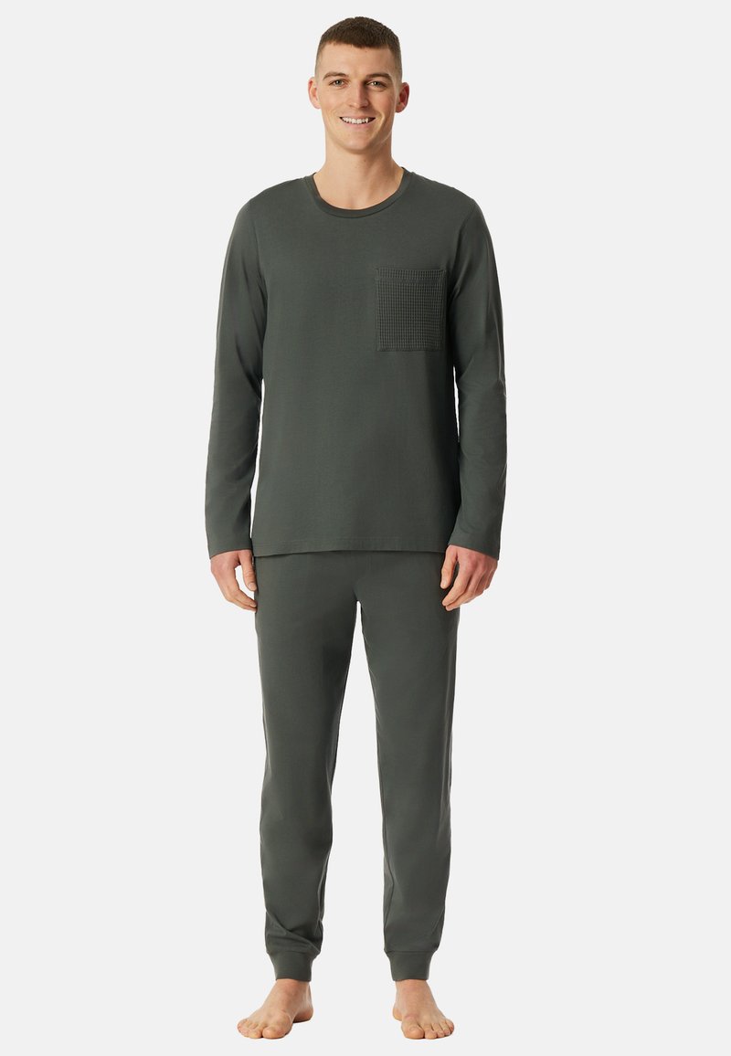 Conjunto de pijama para hombre en verde oscuro, hecho de tela suave, que incluye una camiseta de manga larga con un bolsillo texturizado y pantalones ajustados a juego.
