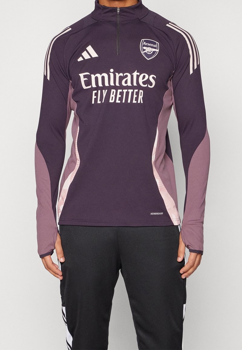 Langärmliges Sportoberteil in dunkelpurpur mit hellrosa Akzenten. Verfügt über einen hohen Kragen, einen Reißverschluss und das Arsenal-Logo auf der Brust.