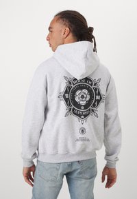 Sweatshirt à capuche gris avec un grand graphisme noir au dos, présentant un design floral et du texte. Tissu : mélange de coton. Poignets et ourlets côtelés.