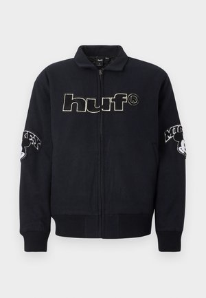 Marineblaue Bomberjacke mit Reißverschluss, gerippten Bündchen und Saum. Verfügt über ein großes "huf"-Logo auf der Vorderseite und einen gestickten Mickey-Mouse-Detail auf den Ärmeln.