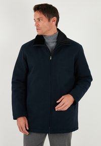 Jūras zila mētelis ar mīkstu apkakli, ar rāvējslēdzēju un brīvu piegriezumu. Izgatavots no gludas auduma, ar sānu kabatām un vidēju garumu.