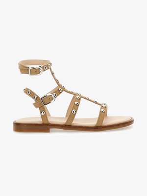 Rudos odinės gladiatorių sandalai su daugeliu dirželių ir sidabro tono smeigėmis. Turi reguliuojamus kulkšnies dirželius ir plokščią padą.