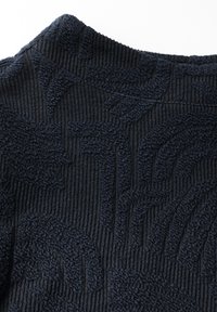 Tissu texturé bleu marine foncé avec un motif côtelé et un design abstrait subtil. Le matériau semble doux et épais, adapté pour des vêtements d'extérieur.