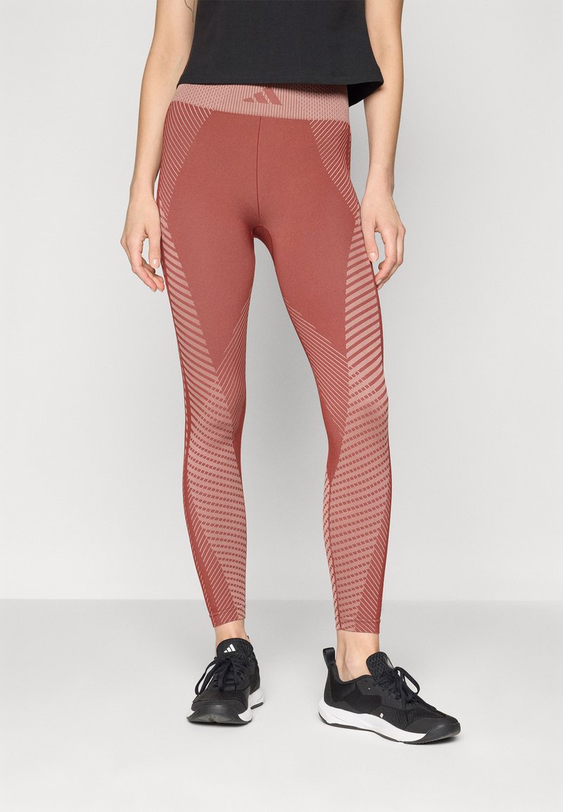 Leggings de fitness rouges avec un motif texturé comprenant des motifs diagonaux et des pois. Ils disposent d'une taille haute et d'une coupe ajustée.