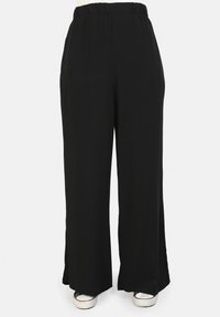 Pantaloni neri a gamba larga realizzati in tessuto morbido con vita elasticizzata, dotati di spacchi laterali all'orlo e una texture liscia.