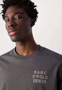Grijze katoenen sweatshirt met een geribbelde ronde hals en het schermgedrukte "MARC O'POLO DENIM"-label in een contrasterende lichte kleur op de borst.
