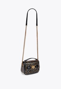 Borsa a tracolla in pelle verniciata nera con accenti dorati, dotata di una tracolla a catena, motivo a pois e chiusura frontale. Forma rettangolare.