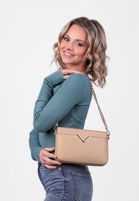 Béžová kabelka s hladkým koženým povrchem, zlatými akcenty a předním V-čelním detailem; disponuje řetízkovým popruhem pro nošení na rameni.