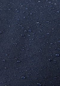 Navy wodoodporna tkanina o teksturowanej powierzchni, z kroplami wody na jej powierzchni. Materiał wydaje się być wytrzymały i mocno tkany.