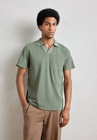Korte erm, olivengrønn polo skjorte laget av glatt stoff, med v-hals og en lomme på venstre bryst. Enkel design uten mønstre.