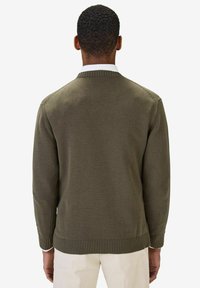 Kaki stickad tröja med ribbad krage och mudd. Slät textur, enkelt mönster och rena linjer. Odekorerad bakvy.