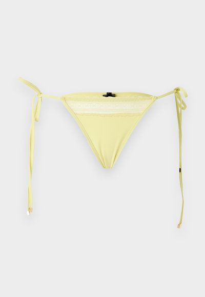 Κίτρινο κάτω μέρος μπικίνι με δαντελένιο τελείωμα και πλαϊνούς δεσίματα σε απλό λευκό φόντο.