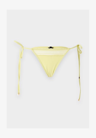 Κίτρινο κάτω μέρος μπικίνι με δαντελένιο τελείωμα και πλαϊνούς δεσίματα σε απλό λευκό φόντο.