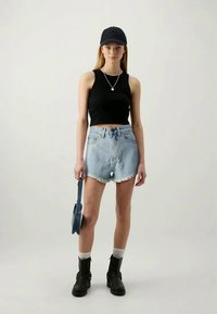 Melna cropped top, gaiši zili džinsa šorti ar saplēstām malām, melna cepure, sudraba apli auskari un melni potītes zābaki ar baltām zeķēm.