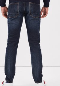 Donkerblauwe denim jeans met een rechte pasvorm, voorzien van twee achterzakken, gestikte details en een gladde textuur.