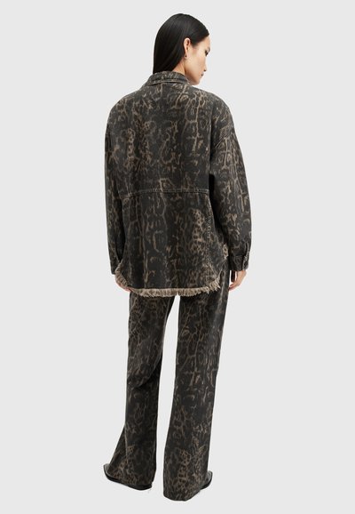 Veste en denim noir et pantalon avec un motif léopard, présentant des bords effilochés et une coupe décontractée, dans des couleurs sombres et une texture riche.