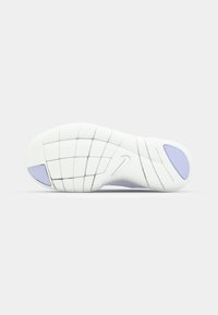 Semelle en caoutchouc blanc avec une texture antidérapante, présentant un motif en grille et des accents lavande. Comprend un logo Nike près du talon.