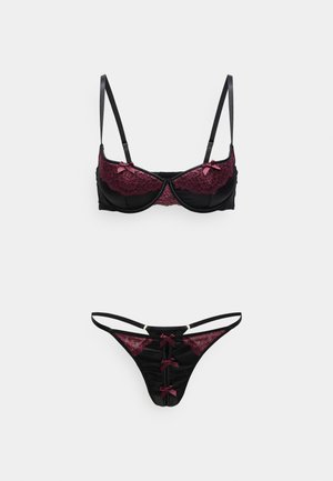 Zwart bh- en slipjes lingerieset met donkerrode kantdetails en kleine strikjes op een effen witte achtergrond.