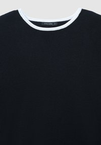 Schwarzes Strickoberteil mit Rundhalsausschnitt, das eine kontrastierende weiße Einfassung am Kragen aufweist. Der Stoff wirkt weich und leicht strukturiert.