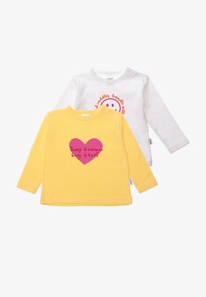 Zwei langärmelige Kleinkindshirts: eins gelb mit einem pinken Herzgrafik und eins weiß mit einem lächelnden Gesicht und orangefarbigem Text. Aus Baumwollmaterial.