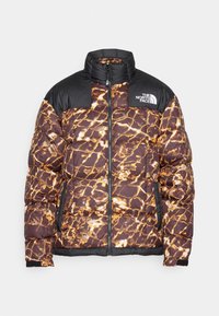 Hnědá a černá péřovka s oranžovým a bílým prasklým vzorem, zapínání na zip a logo The North Face na hrudi.