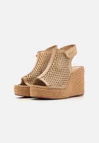 Sandales compensées beiges avec tige perforée, open toe et strap à la cheville. Semelle en jute tissé naturel et semelle texturée. Détail en logo doré.