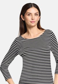 Schwarz-weißer gestreifter Oberteil mit Bootsausschnitt und dreiviertel Ärmeln, ausgestattet mit einer weichen, glatten Textur und einer figurschmeichelnden Passform.