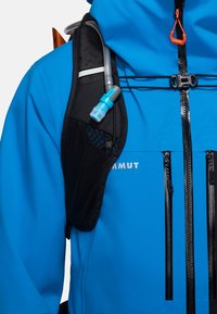 Giacca impermeabile blu con tasca in rete nera, tubo per idratazione e cinghie regolabili. Presenta due cerniere verticali e accenti riflettenti.