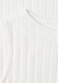 Tissu tricoté blanc côtelé avec détail de couture diagonale, montrant la texture et le motif en gros plan.