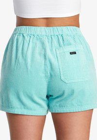 Lyseblå fløjlsshorts med elastisk talje og en enkelt baglomme med et sort RVCA-logo. Lodret ribbet tekstur.