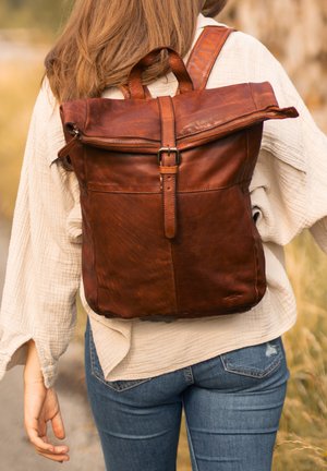 Pruun nahkne seljakott, millel on rulli ülaosa disain, reguleeritavad sangad ja eesmine tõmblukk. Omab siledat tekstuuri ja tugevat õmblust.